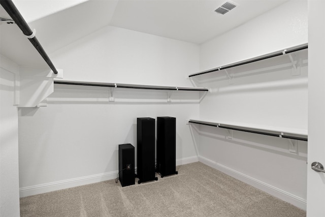 spacious closet with lofted ceiling and light carpet