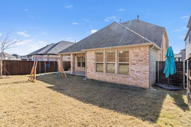 rear view of property with a playground and a lawn