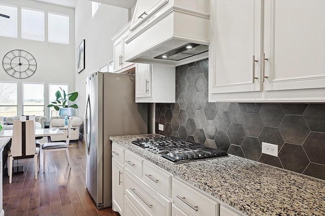 kitchen featuring premium range hood, white cabinetry, appliances with stainless steel finishes, and tasteful backsplash