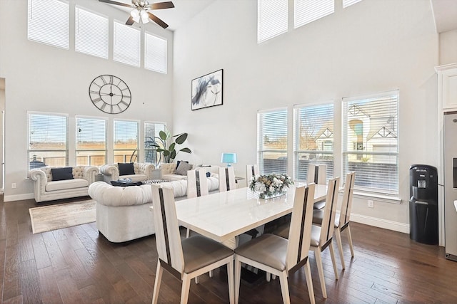 dining room with ceiling fan, a high ceiling, and dark hardwood / wood-style floors