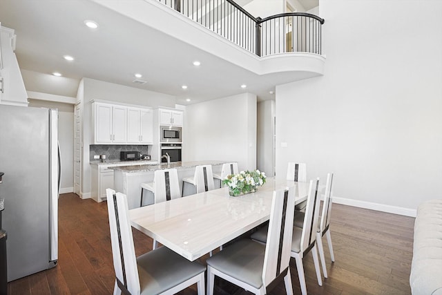 dining space featuring sink, a high ceiling, and dark hardwood / wood-style flooring