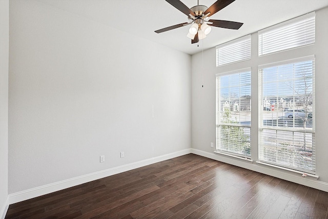 spare room featuring ceiling fan, a wealth of natural light, and dark hardwood / wood-style flooring