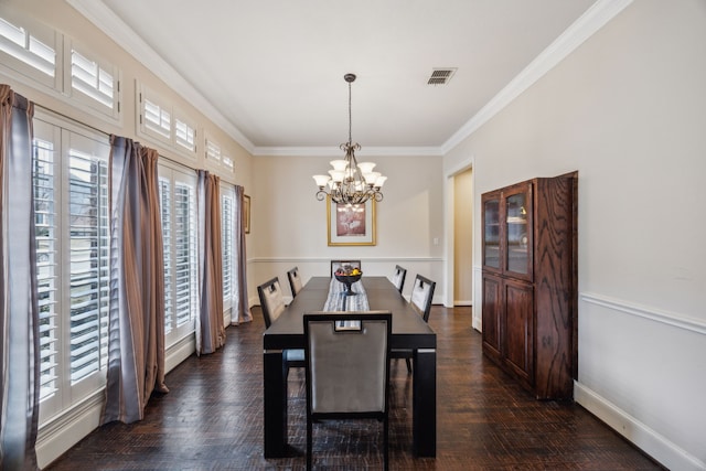 dining space with dark hardwood / wood-style flooring, ornamental molding, and an inviting chandelier