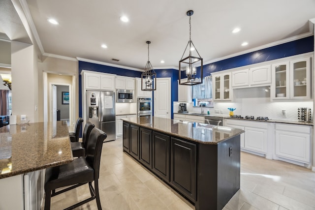 kitchen featuring white cabinets, appliances with stainless steel finishes, dark stone countertops, sink, and hanging light fixtures