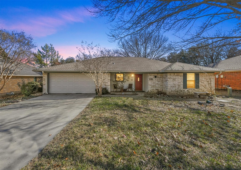 single story home featuring a garage and a lawn