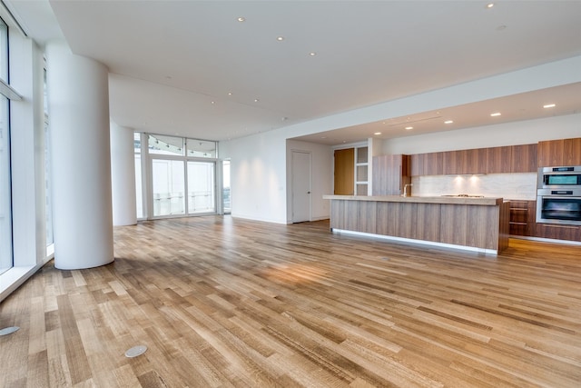 unfurnished living room with light wood-type flooring and floor to ceiling windows