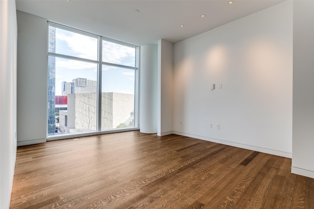 empty room with hardwood / wood-style flooring, plenty of natural light, and expansive windows