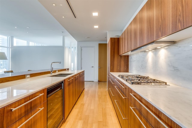 kitchen with light hardwood / wood-style floors, stainless steel gas cooktop, sink, backsplash, and wine cooler