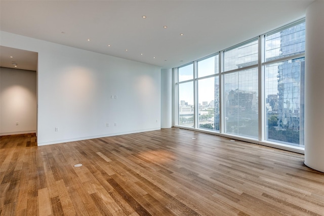 empty room featuring a wall of windows and light hardwood / wood-style floors