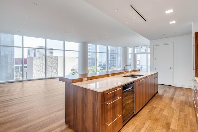 kitchen featuring sink, light hardwood / wood-style floors, expansive windows, and a large island