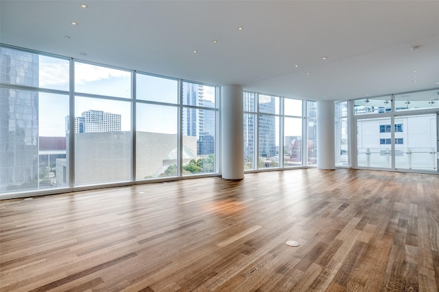 unfurnished living room featuring a wall of windows, light wood-type flooring, and a wealth of natural light