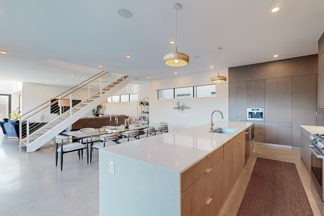 kitchen with wooden walls, sink, hanging light fixtures, stainless steel appliances, and a spacious island