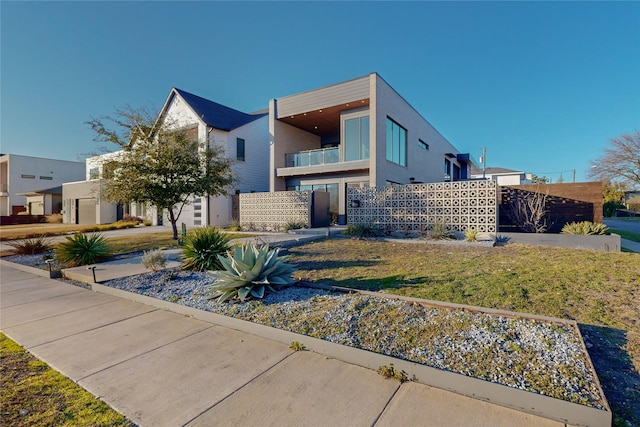 modern home with a balcony and a front lawn