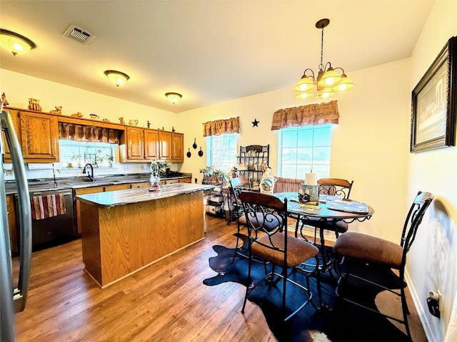 kitchen featuring a kitchen island, wood-type flooring, an inviting chandelier, sink, and hanging light fixtures