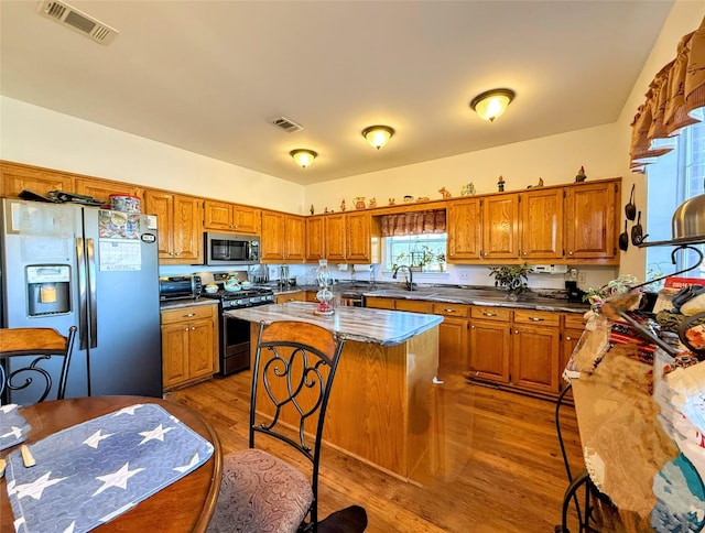 kitchen featuring light stone countertops, hardwood / wood-style floors, appliances with stainless steel finishes, and a center island