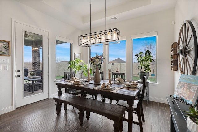 dining space featuring dark hardwood / wood-style flooring, a tray ceiling, and a chandelier