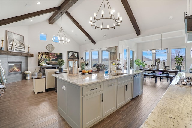 kitchen featuring sink, an inviting chandelier, decorative light fixtures, a center island with sink, and dishwasher