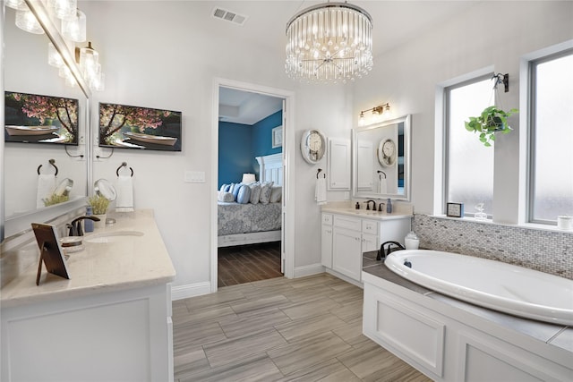 bathroom with vanity, a chandelier, decorative backsplash, and a washtub