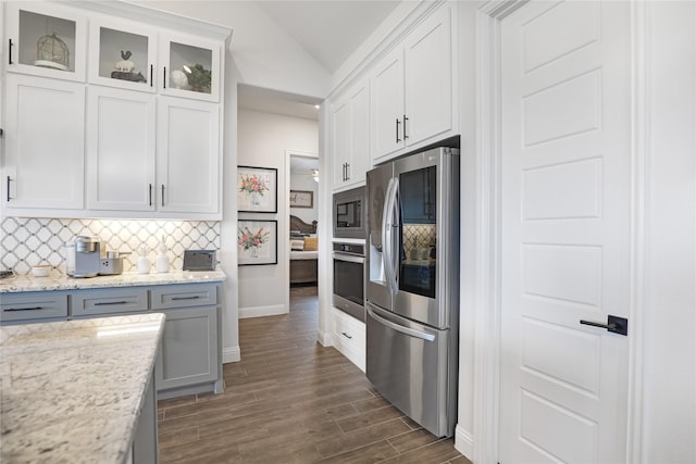 kitchen with appliances with stainless steel finishes, dark hardwood / wood-style floors, white cabinetry, decorative backsplash, and light stone counters