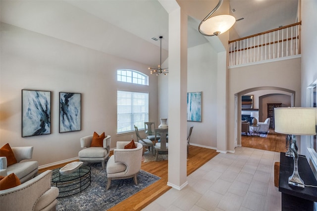 living room with a high ceiling, a notable chandelier, and light wood-type flooring