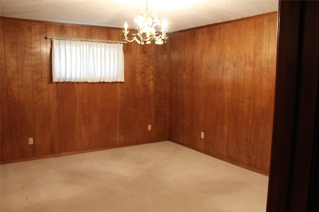 carpeted empty room featuring a textured ceiling, wooden walls, and a notable chandelier