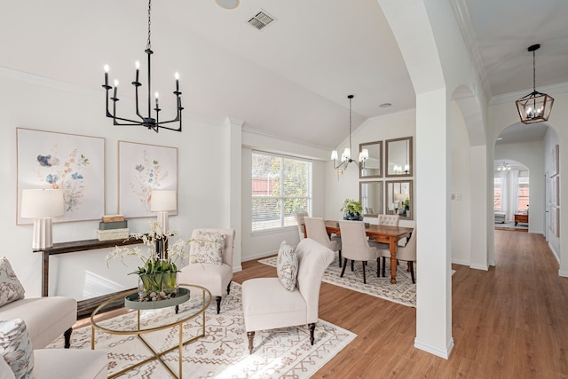 living room with lofted ceiling, hardwood / wood-style floors, a notable chandelier, and ornamental molding