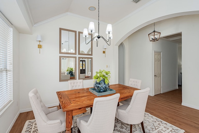 dining room with crown molding, hardwood / wood-style floors, and a chandelier