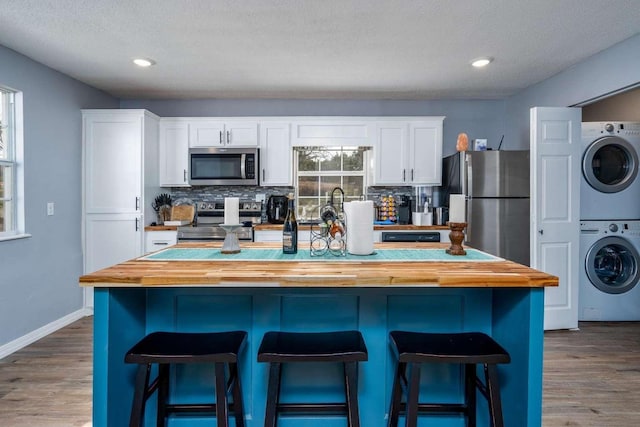 kitchen with white cabinets, appliances with stainless steel finishes, wooden counters, and a kitchen bar