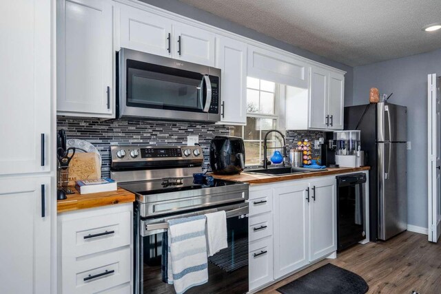 kitchen with sink, wooden counters, backsplash, stainless steel appliances, and white cabinets