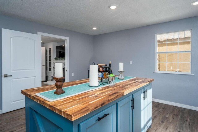 kitchen featuring wood counters, blue cabinets, dark hardwood / wood-style flooring, ceiling fan, and a textured ceiling