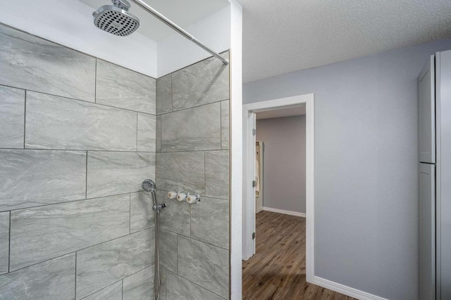 bathroom with a tile shower, hardwood / wood-style floors, tasteful backsplash, vanity, and toilet