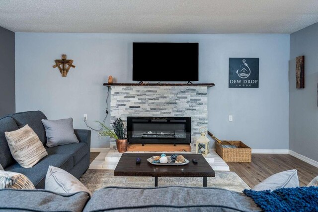 living room with a stone fireplace, light wood-type flooring, ceiling fan, a textured ceiling, and french doors