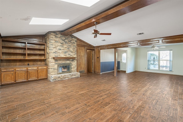 unfurnished living room with a brick fireplace, vaulted ceiling with skylight, and ceiling fan