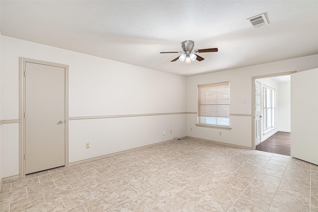 empty room with ceiling fan and a textured ceiling