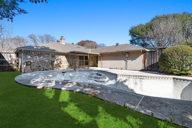 back of house with an empty pool, a yard, and a patio