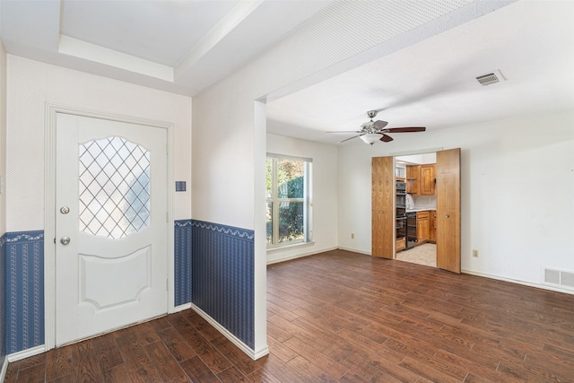 entrance foyer featuring ceiling fan, a raised ceiling, and dark wood-type flooring