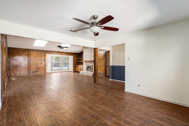 unfurnished living room featuring ceiling fan, dark hardwood / wood-style floors, and a fireplace