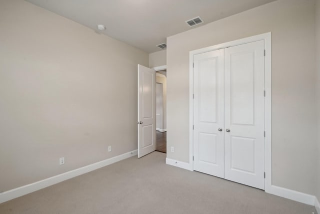 unfurnished bedroom with light colored carpet and a closet