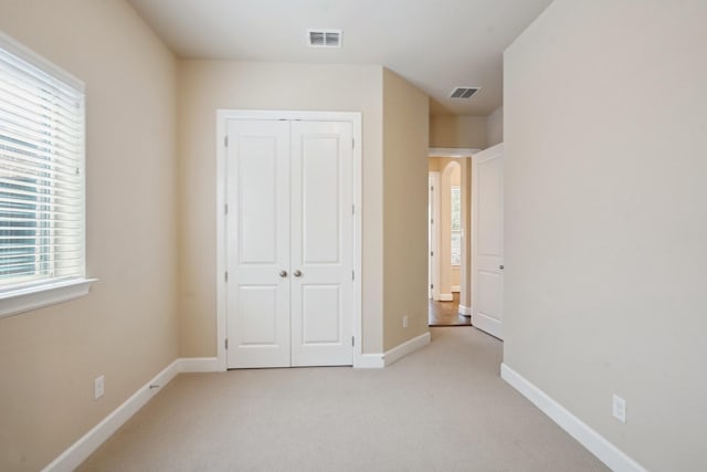 unfurnished bedroom featuring light colored carpet and a closet