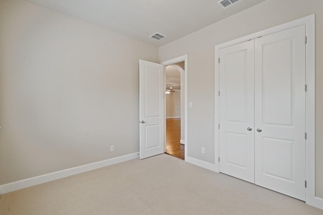 unfurnished bedroom with light colored carpet and a closet