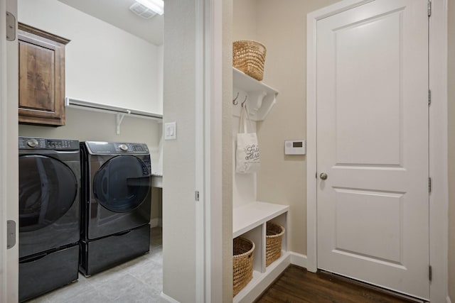 clothes washing area featuring washer and clothes dryer and cabinets