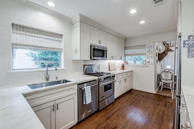 kitchen with sink, appliances with stainless steel finishes, white cabinetry, ornamental molding, and decorative backsplash