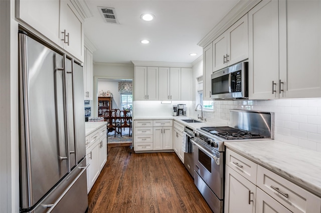 kitchen featuring sink, white cabinetry, tasteful backsplash, high quality appliances, and dark hardwood / wood-style flooring