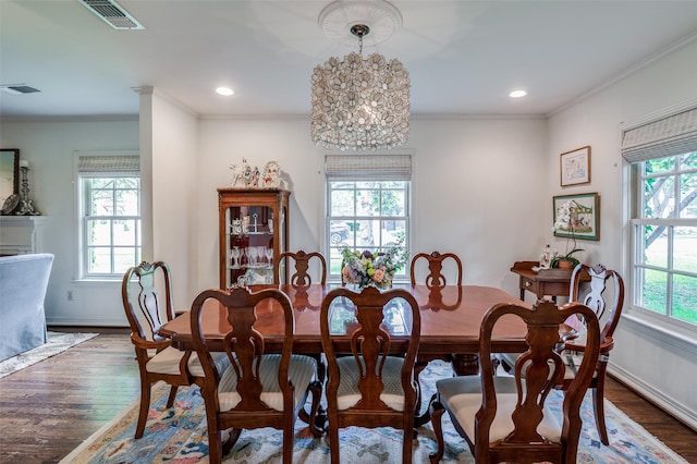 dining space with a healthy amount of sunlight, dark hardwood / wood-style floors, an inviting chandelier, and ornamental molding