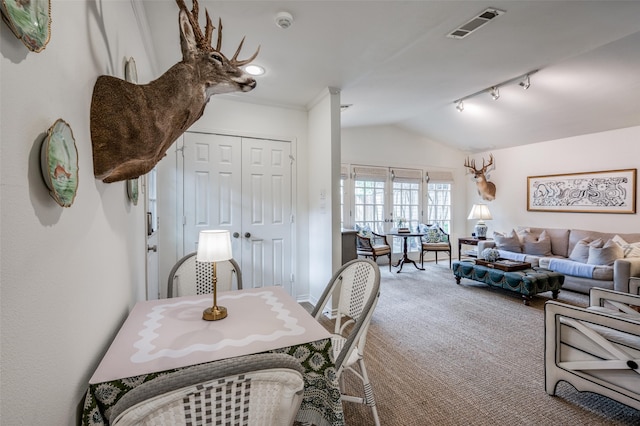 carpeted dining space with lofted ceiling and track lighting