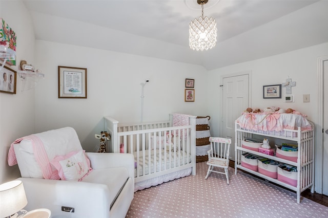 bedroom featuring an inviting chandelier, carpet flooring, vaulted ceiling, and a crib