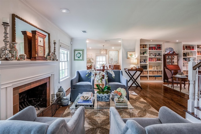 living room with hardwood / wood-style floors, built in features, a fireplace, and ornamental molding