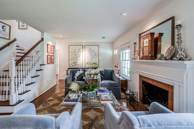 living room with crown molding, wood-type flooring, and a tiled fireplace