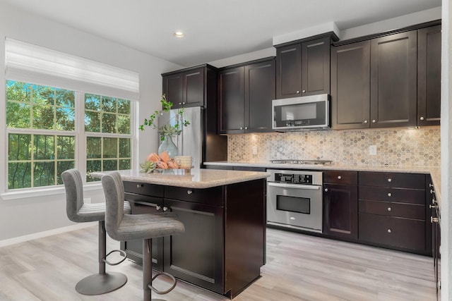 kitchen featuring light hardwood / wood-style floors, dark brown cabinetry, stainless steel appliances, and tasteful backsplash