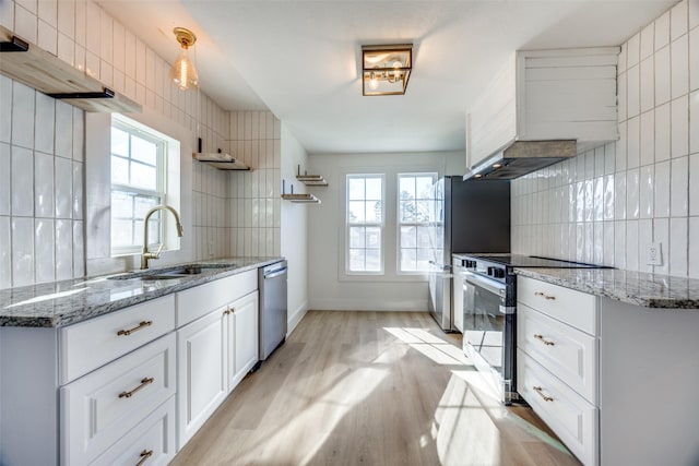 kitchen featuring sink, white cabinetry, dark stone counters, decorative backsplash, and stainless steel appliances